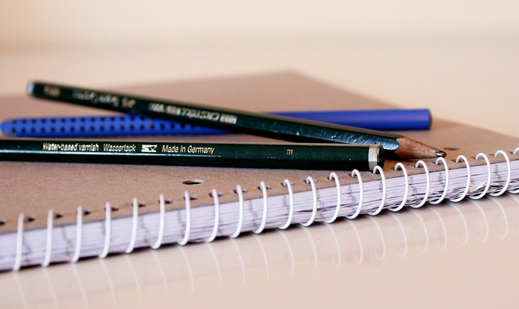 imagem de um caderno com alguns lápis em cima
