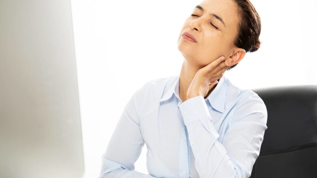 Mulher com dor no pescoço durante o trabalho podendo ser enquadrado como doença ocupacional