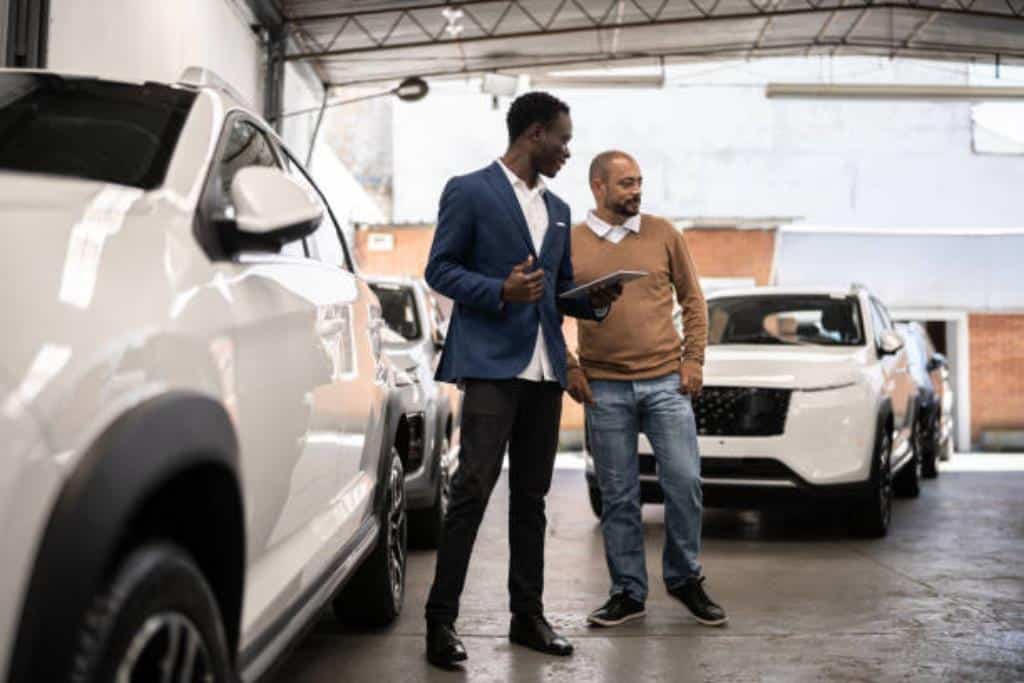 vendedor de carro mostrando modelos para um cliente