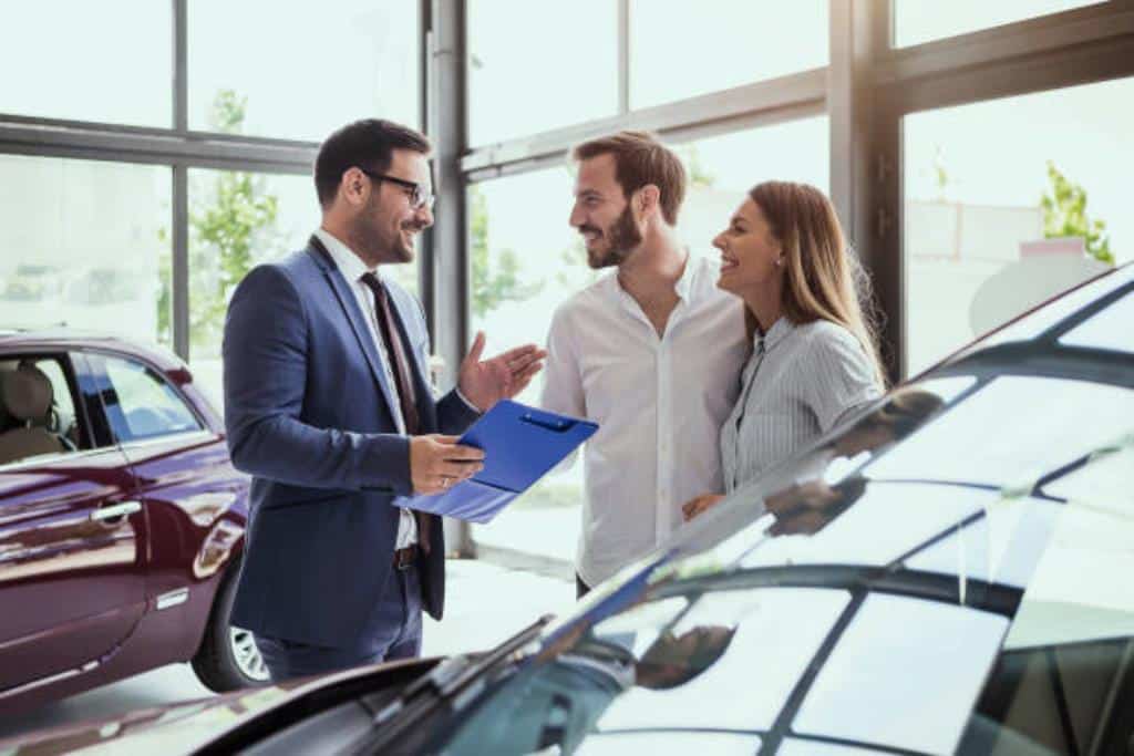 vendedor de carro falando com um casal