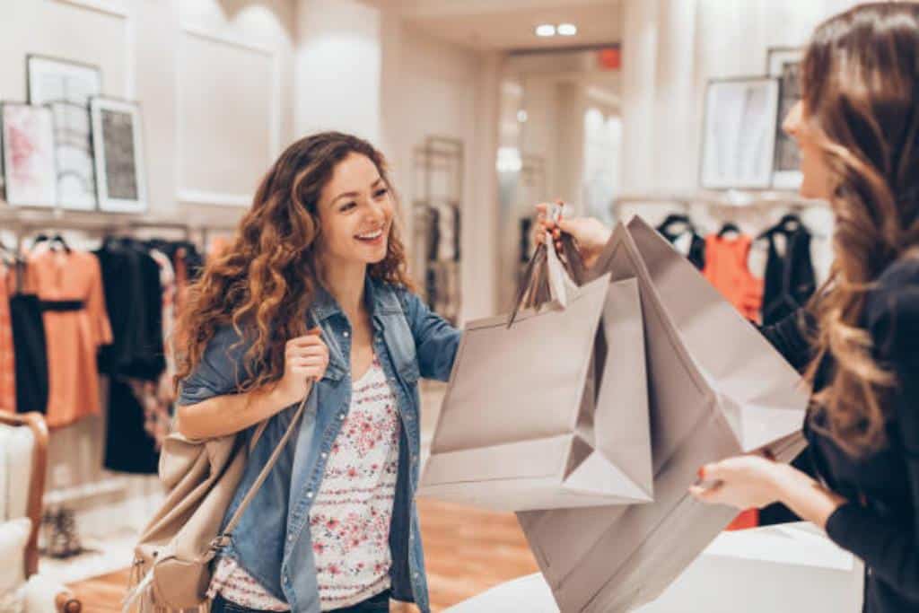 vendedora entregando sacolas de compra para cliente