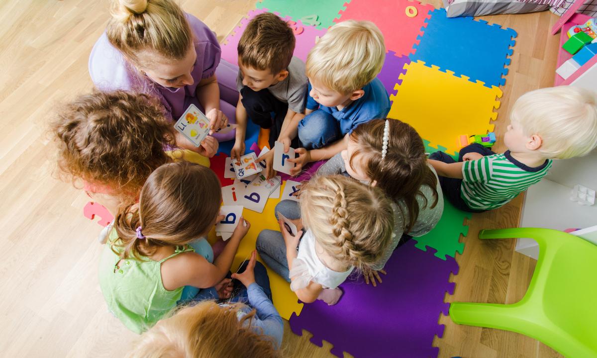 educadora em sala infantil com várias crianças ao seu redor