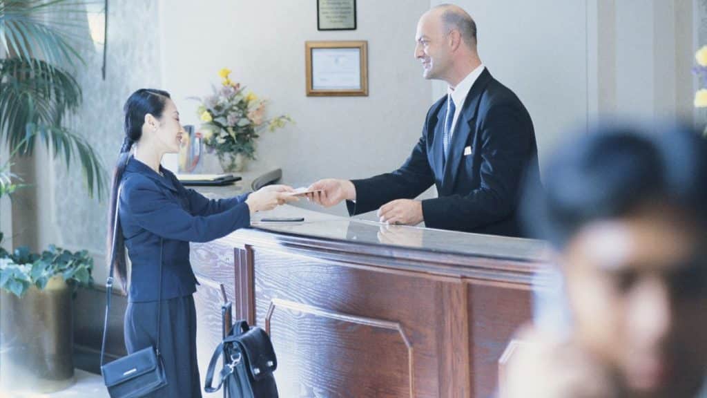 porteiro atendendo um cliente na recepção de um hotel.