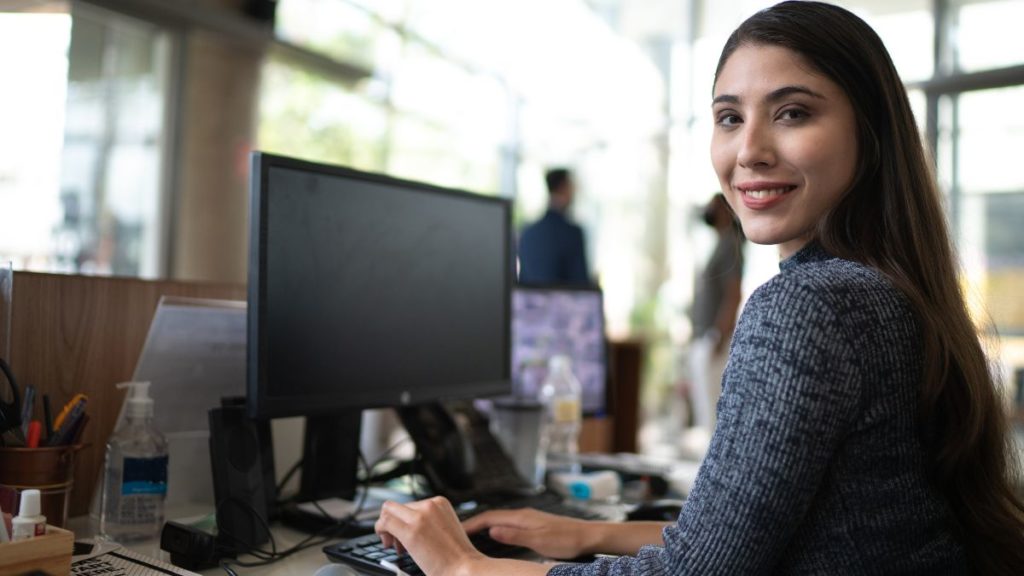 recepcionista utilizando o computador em seu local de trabalho.