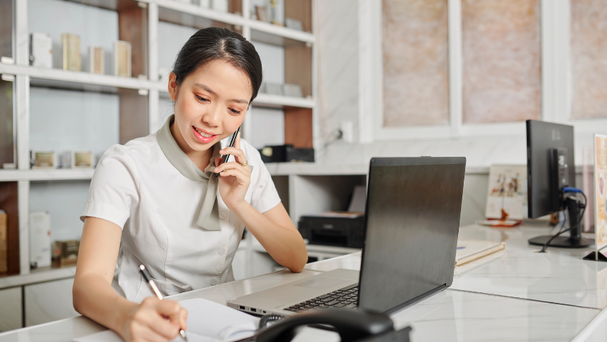 recepcionista fazendo anotações enquanto esta ao telefone