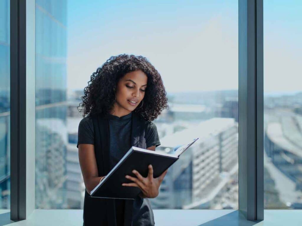 Dona de empresa segurando e lendo um livro sobre quais expressões ela deve evitar no ambiente profissional.