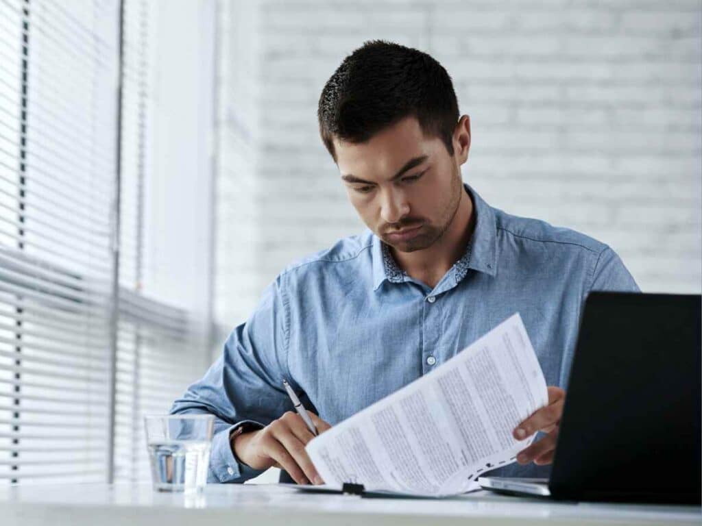 Ex-funcionário lendo e assinando um acordo legal feito com sua empresa.