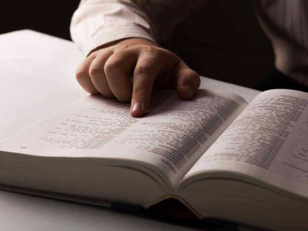 Pessoa lendo o novo acordo ortográfico, pesquisando no livro informações sobre o uso de "Fim de Semana" ou "Final de Semana"