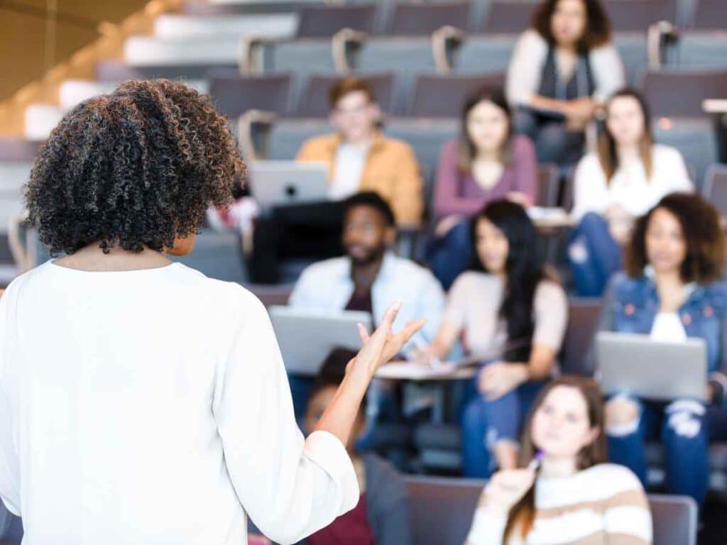 Mulher dando palestra em uma empresa sobre a importância de evitar expressões pejorativas.