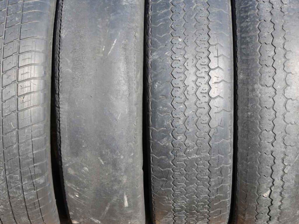 Quatro pneus de carro com desgaste visível na borracha, mostrando falta de sulcos e irregularidades no desgaste.