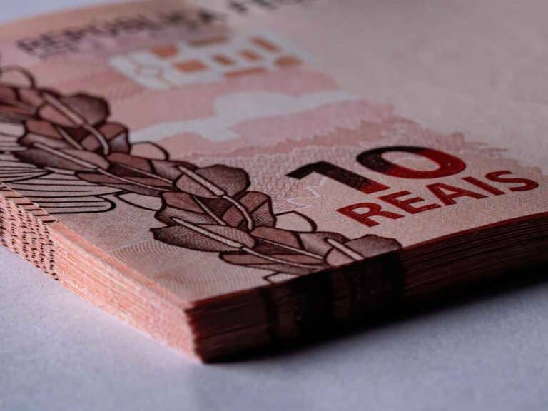 Imagem de várias cédulas de 10 reais empilhadas, mostrando detalhes da borda, do valor impresso e dos elementos gráficos da nota.