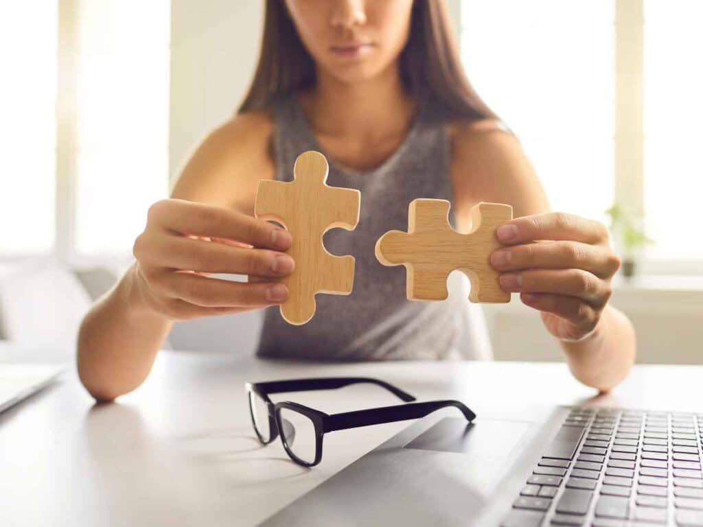 Mulher segurando duas peças de quebra-cabeça prestes a serem encaixadas, simbolizando o processo de resolução de problemas