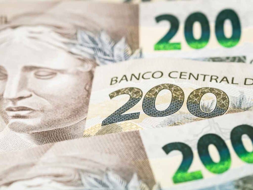 Close em diversas cédulas de 200 reais, com o número “200” e elementos gráficos da nota em evidência.