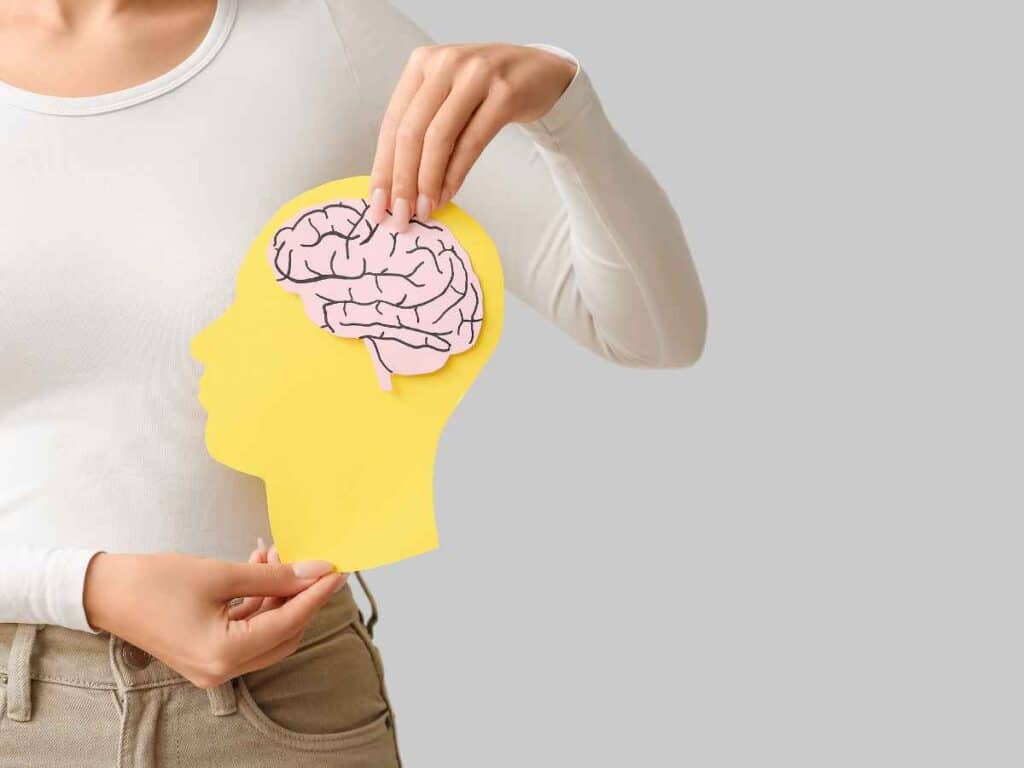 Mulher segurando silhueta amarela com cérebro em destaque