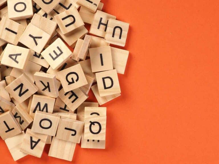 Blocos de madeiras com letras contra fundo laranja.