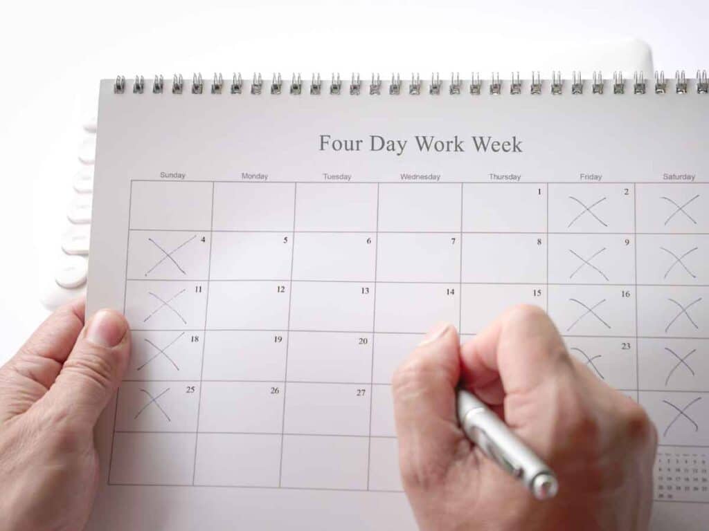 Mãos segurando um calendário com marcações indicando dias trabalhados e folgas, representando planejamento semanal e controle da rotina de trabalho.