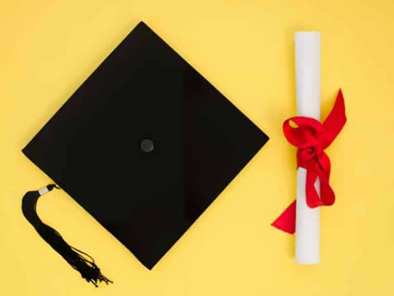 Chapéu de formatura ao lado de certificado de conclusão de curso