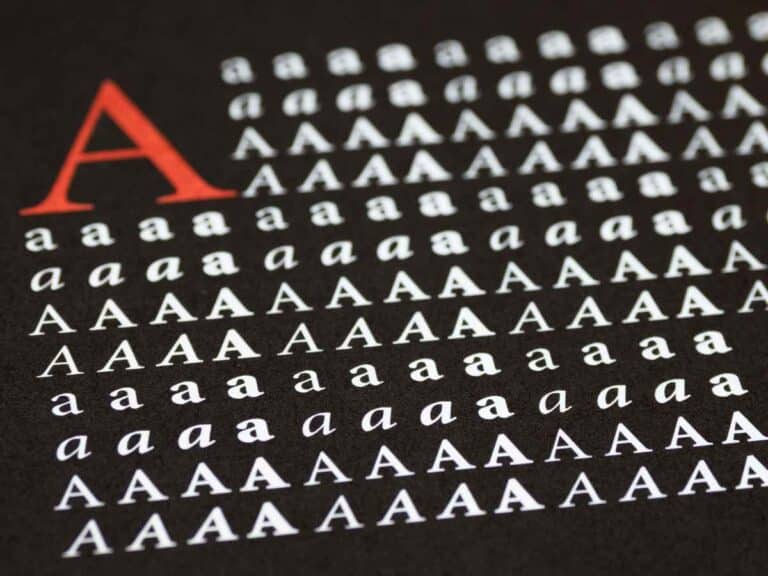 Várias letras “a” em diferentes tamanhos (maiúsculo e minúsculo) e estilos tipográficos sobre fundo escuro, com destaque para a letra “A” em vermelho