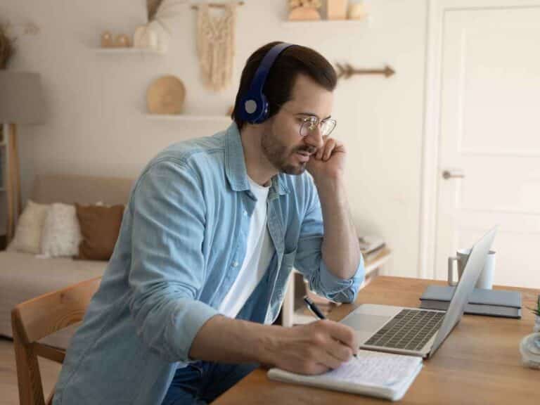 Homem usando fones de ouvido enquanto estuda ou faz curso online no notebook