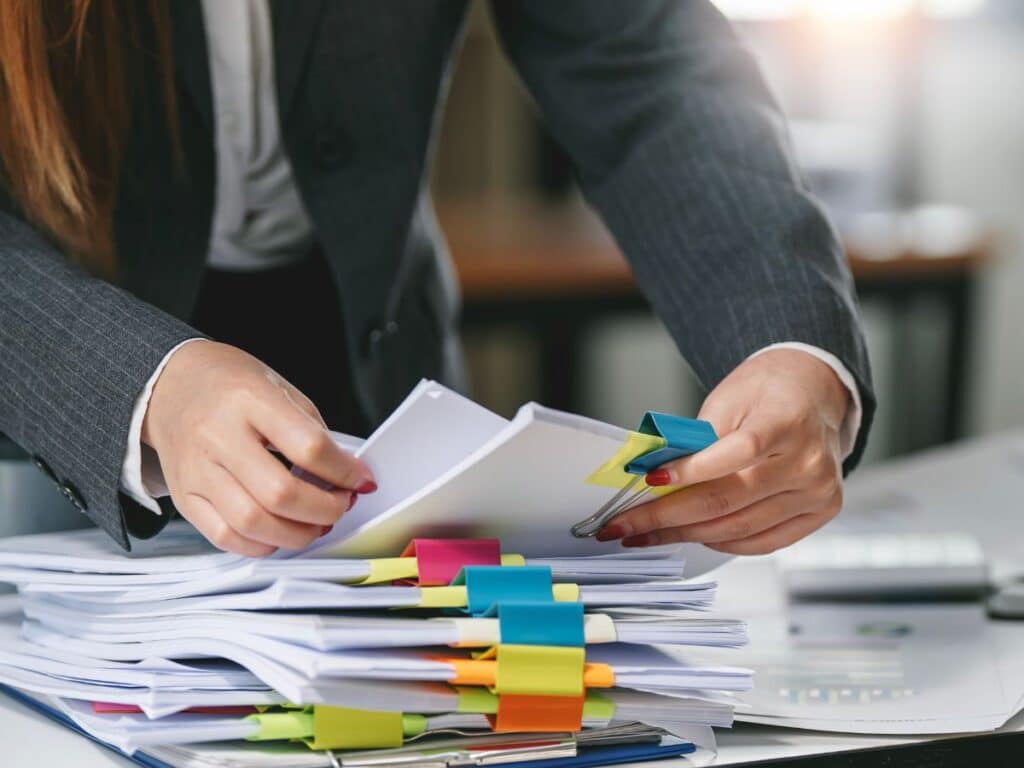 Mulher organizando documentação sst com prendedores coloridos