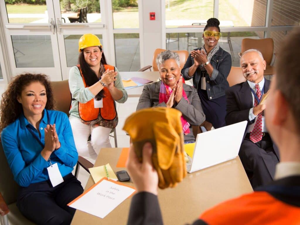 Grupo de colaboradores participa de um treinamento sobre segurança no trabalho em uma sala de reuniões.